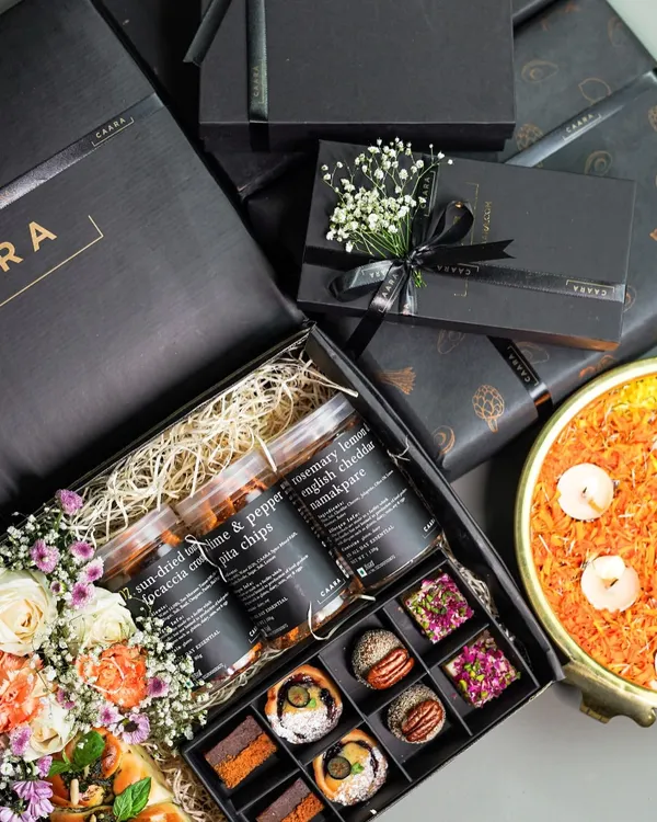 A look inside our signature Sancho Box for Diwali, a true celebration of flavour. This gourmet gift hamper features an assortment of our modern Indian sweet bites alongside savoury jars of sun-dried tomato & pepper focaccia chips and rosemary lemon English cheddar namakpare, all beautifully arranged with fresh flowers.