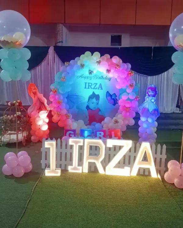 For Irza's first birthday, we created this magical setup with a circular balloon arch and a custom photo backdrop. The large light-up letters spelling her name and age became the perfect centerpiece for the party.