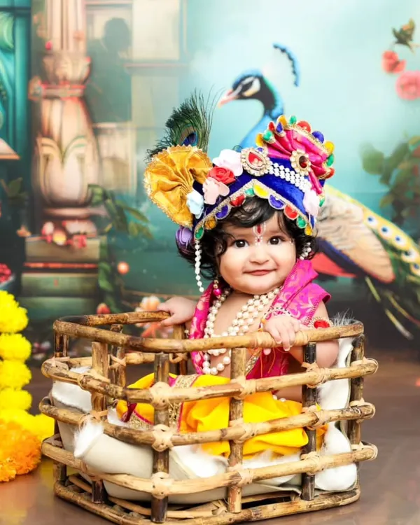 Dressed as little Lord Krishna, this baby's divine smile is captivating. The detailed costume and vibrant backdrop make for a stunning Janmashtami portrait.