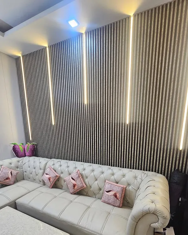 I transformed this living room with a stunning feature wall using dark, fluted WPC panels. The integrated vertical LED strip lighting creates a warm, luxurious atmosphere and adds depth to the space, making it perfect for a modern home. This is a great way to create a high-end look.