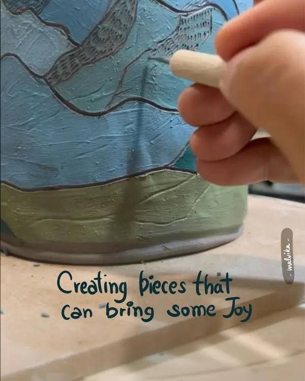 A close-up of creating pieces that bring joy. Here, I am using a carving tool to etch a mountain landscape onto a mug. This surface decoration technique adds a personal and artistic touch.
