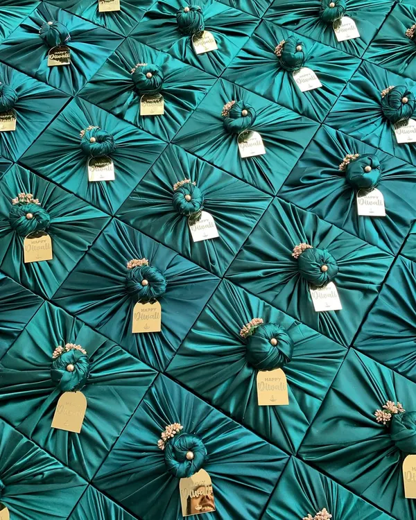 The visual power of beautiful packaging. This large order of corporate gifts, each wrapped in luxurious teal satin with a custom gold tag, creates a stunning and memorable impression.