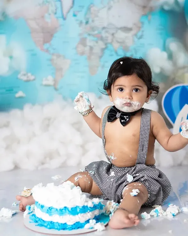 Let the smashing begin. This little one is diving right into his first birthday cake during our popular travel-themed cake smash session.