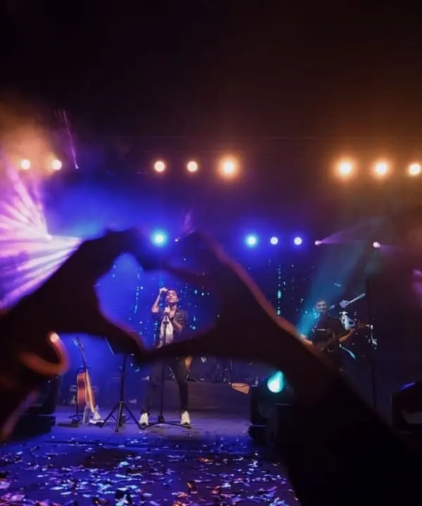 A creative shot from the crowd, forming a heart with hands around the artist on stage. This image perfectly captures the love and adoration of fans at a college fest.