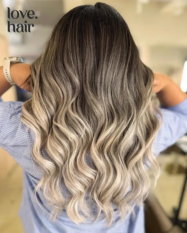Sipping bubbly, feeling lovely, living lovely. This stunning champagne blonde balayage is the epitome of glamour, with a seamless melt from dark roots to platinum ends.