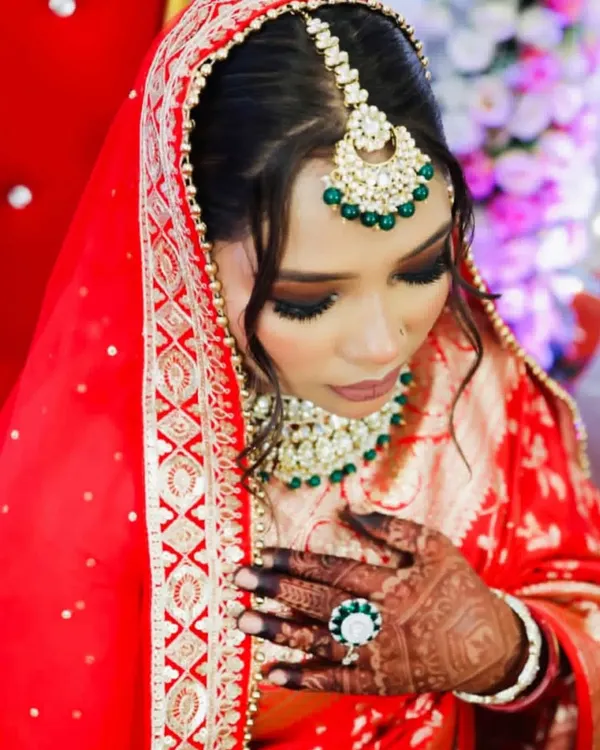A complete view of a traditional bridal look I created. The rich red dupatta frames her face beautifully, highlighting the bold eye makeup and the intricate kundan and emerald jewelry. My goal is to ensure your makeup works in harmony with your entire bridal ensemble.