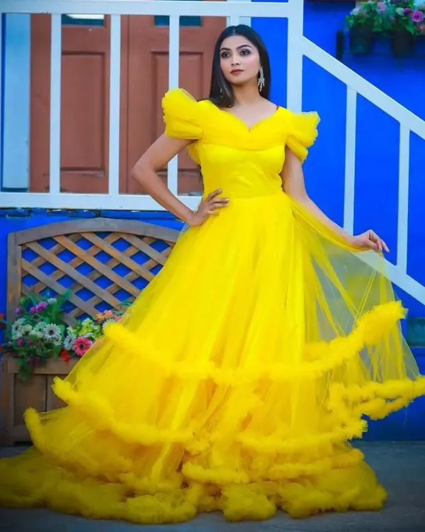 Make a grand entrance with this stunning yellow ball gown, available for rent. The ruffled sleeves and voluminous tiered skirt create a dramatic and unforgettable look.