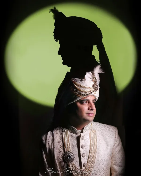 An artistic portrait of the groom with a creative shadow effect, highlighting his traditional sherwani and turban.
