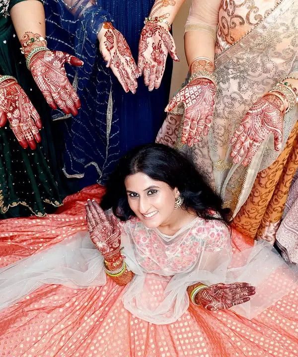 A beautiful and creative Mehndi photo, with the bride surrounded by the henna-adorned hands of her loved ones. This shot symbolizes blessings and togetherness.