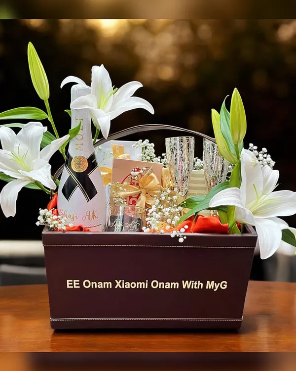 This is a luxury corporate hamper I created for Xiaomi's Onam celebration, presented in a custom-branded leatherette basket with fresh lilies, champagne, and other premium goodies.