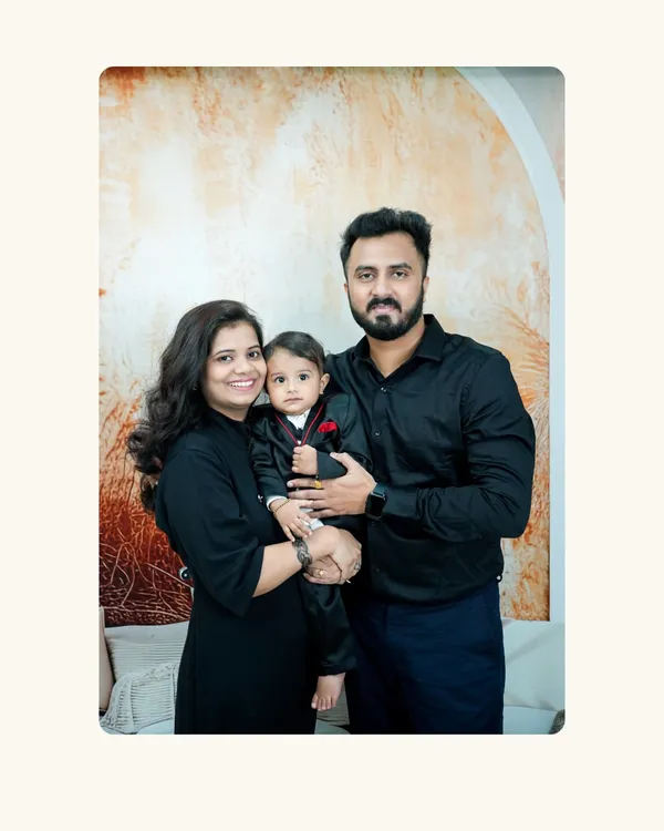 A classic family portrait. The parents and their little one, dressed in matching black outfits, create a timeless and elegant image.