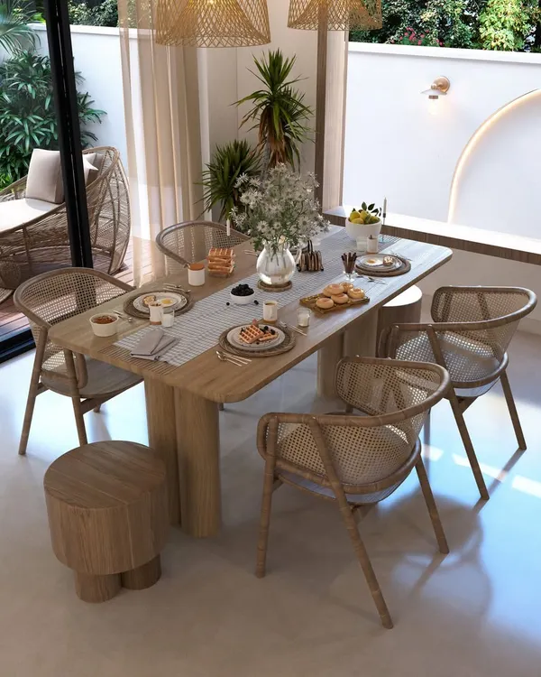 This dining space embodies a natural, bohemian aesthetic that connects directly with the outdoors. We used earthy materials like wood and rattan for the furniture and kept the color palette neutral to complement the view of the green patio just outside the sliding glass doors.