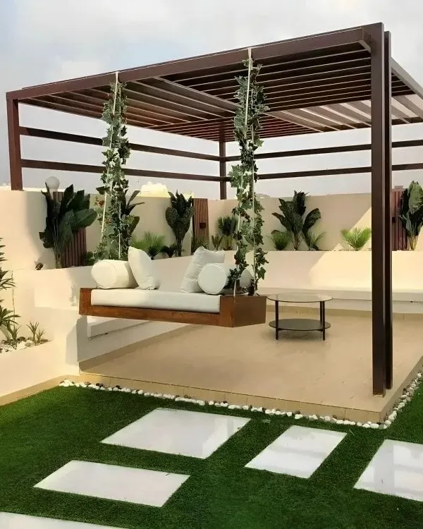 This rooftop terrace design combines natural and modern elements to create a serene escape. I used a dark wood pergola to frame the space, adding a custom-built hanging sofa for ultimate relaxation. The design is completed with artificial turf, white stone pavers for a clean walkway, and built-in planters with lush greenery.