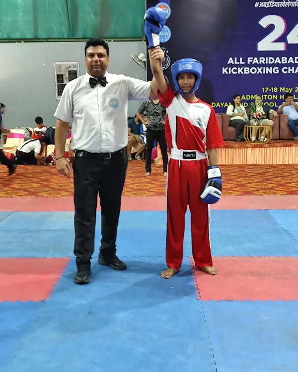 A young champion's hand is raised by the referee after a victorious bout at the 24th Faridabad District Kickboxing Championship. This moment captures the essence of hard work paying off.