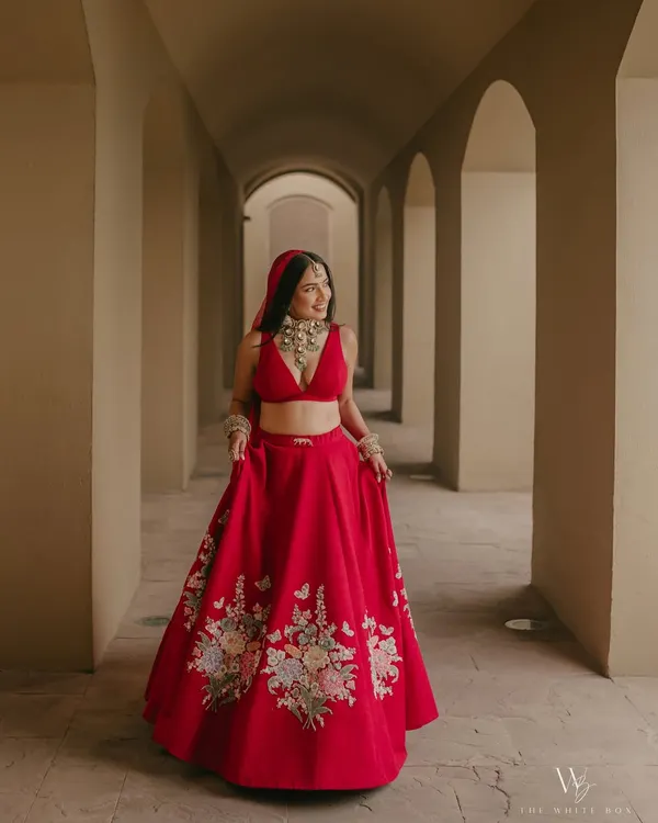 A timeless bridal portrait for Shubhangi at her destination wedding. Her classic red Sabyasachi lehenga was complemented by a radiant, fresh makeup look and a bold lip, perfect for this stunning architectural backdrop. This is a great example of a modern yet traditional bridal style.