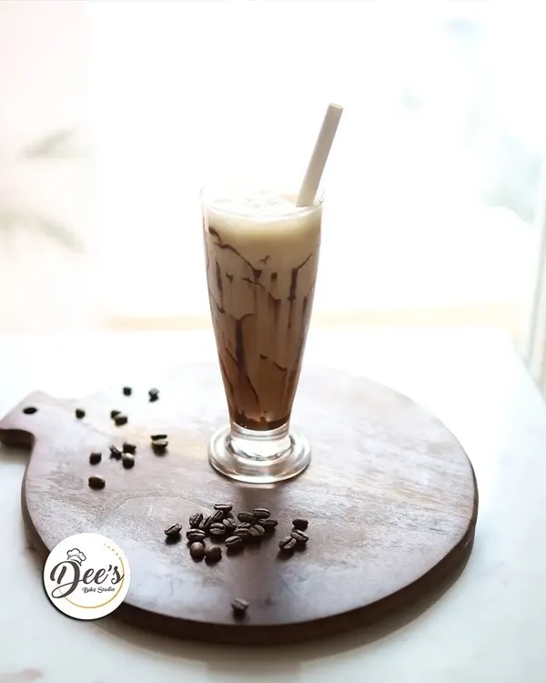 Savor the chill with every sip of our creamy cold coffee. It's the perfect refreshing escape, presented beautifully on a wooden board with coffee beans.