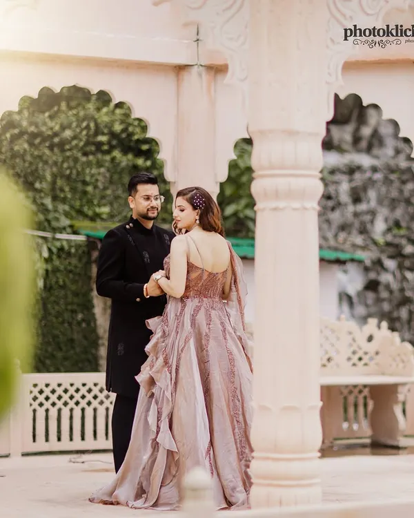 A beautifully lit portrait of a couple in elegant attire, standing within a classic stone gazebo, creating a timeless and romantic feel.