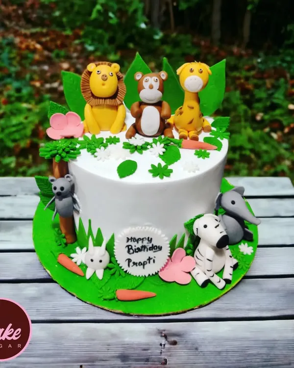 A delightful jungle theme cake set against a natural backdrop. This cake features a whole crew of cute, handcrafted fondant animals including a lion, monkey, giraffe, and zebra.