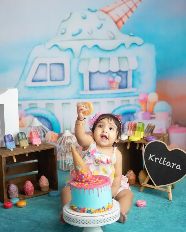 One is sweet. This little girl is celebrating her first birthday with an ice cream themed cake smash. The colorful cake and props create a fun and festive scene.