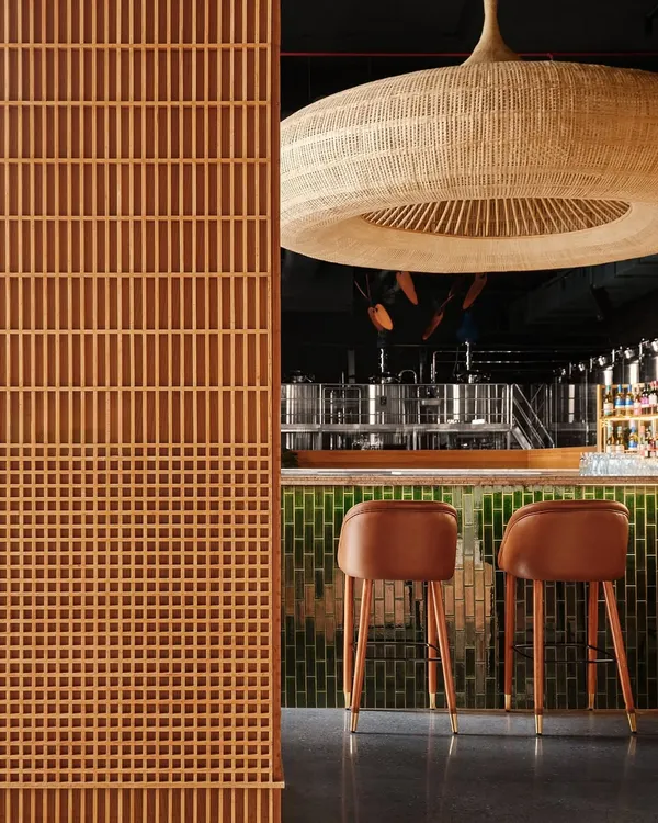 The bar at Biergarten is defined by this oversized, handwoven light fixture, a collaboration with weavers from Kerala. This single element acts as the focal point for the entire microbrewery, demonstrating how we use custom craft to create memorable hospitality experiences.