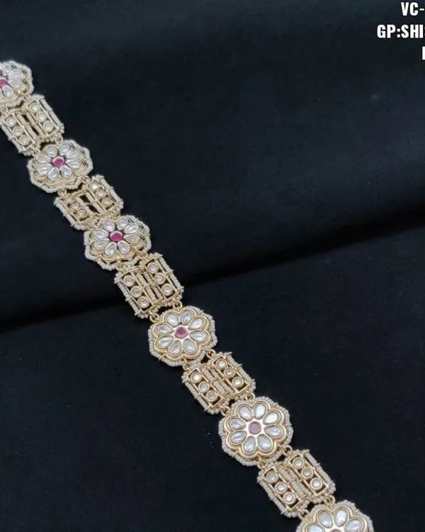 A close-up of a premium quality Kundan sheesh patti with a floral design and red stone center. This hair accessory adds a royal touch to any bridal look.