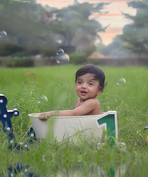 Look at this sweet little one enjoying a bubbly bath in the middle of a lush green field! I love creating these unique outdoor sitter sessions, complete with playful ducklings and floating bubbles for a truly magical experience.