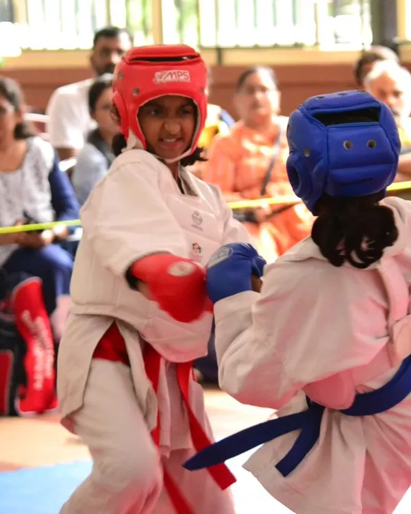 A young competitor stays focused during a tense moment in a kumite match. She wears full protective gear, including a head guard and gloves, ensuring a safe and fair competition.