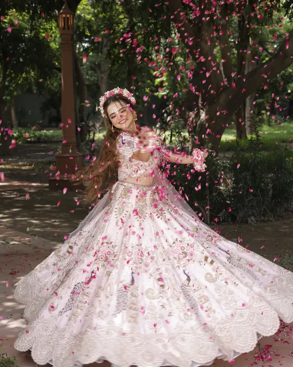A magical shot from our Radha-themed photoshoot. The makeup is soft and ethereal, complemented by a shower of flower petals.
