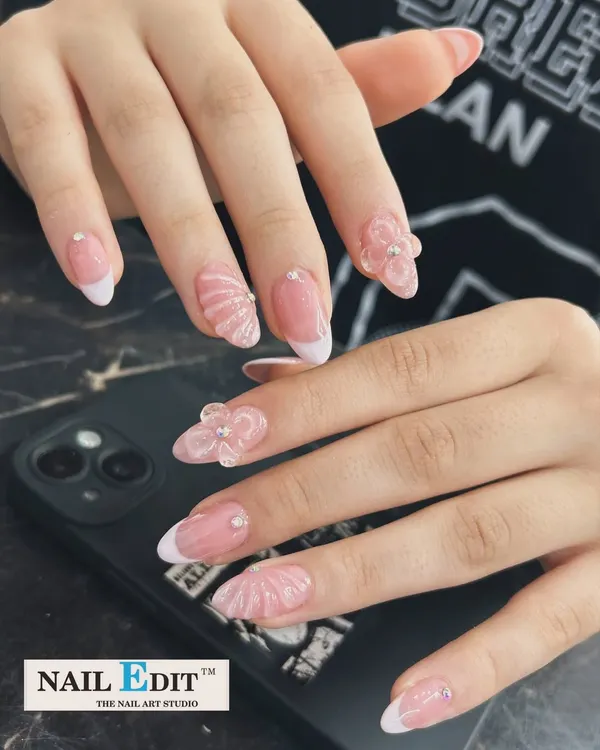 We love elevating a classic French manicure. This design on almond-shaped nails features intricate, hand-sculpted 3D elements, including delicate flowers and seashell textures, for a look that is both elegant and artistic.