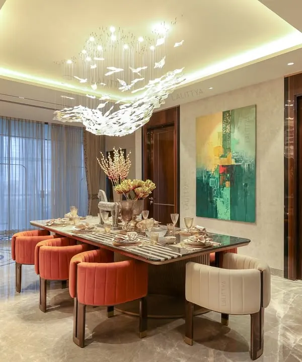 Dinner here always feels a little more special. This 12-foot dining table features a stunning marble top with black and white inlay. It's surrounded by chairs in contrasting rust and white velvet, all sitting under a sculptural chandelier of birds in flight.