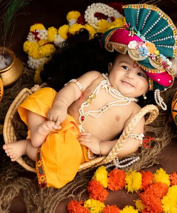 An absolutely adorable baby dressed as Little Krishna for Janmashtami. His joyful smile and playful pose in a basket make this photo truly special.