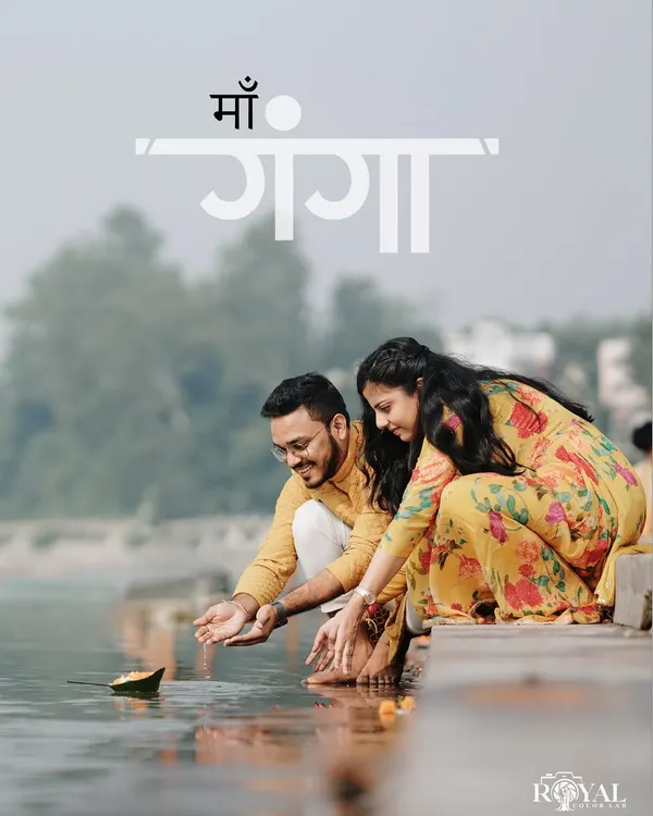 A beautiful, serene shot of a couple in matching yellow ethnic wear offering a diya to the Ganga river, capturing a moment of spiritual connection.