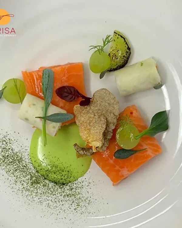 A deconstructed plate featuring cured salmon, fried oyster mushrooms, and grapes with a vibrant green puree. This dish is an example of our modern culinary style, focusing on artistic plating and complex flavor pairings.