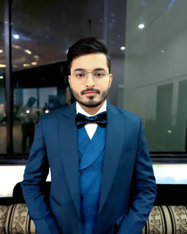 A classic, confident pose from a groom ready for his reception. The deep blue suit is complemented by a clean hairstyle and natural makeup that defines his features without being obvious.