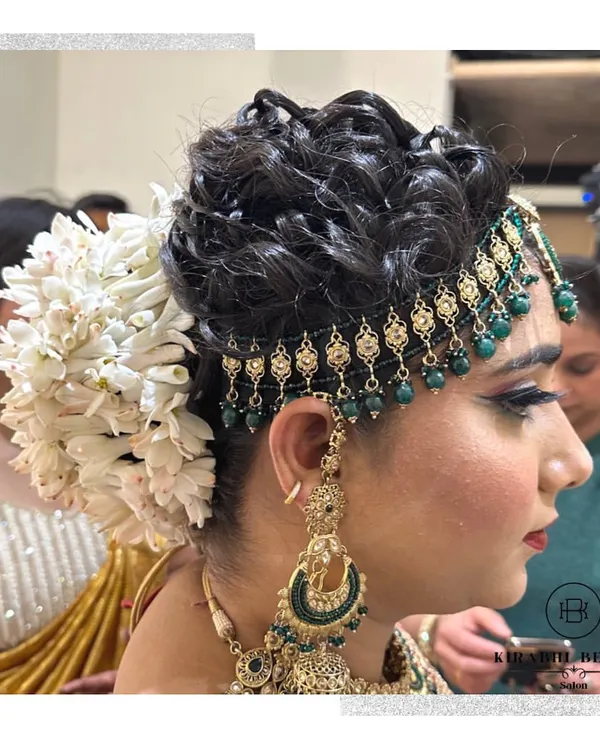 A beautiful and intricate bridal updo. This hairstyle features a classic bun adorned with a large gajra and a traditional matha patti.
