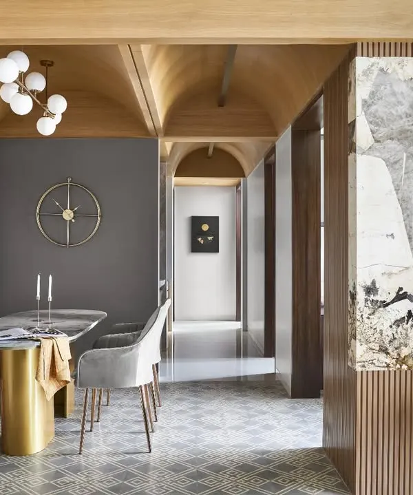 The vaulted ceiling is the defining feature of this apartment, creating a sense of grandeur and warmth. This view shows how it connects the dining area with the rest of the home, complemented by geometric floor tiles and a bespoke marble dining table.