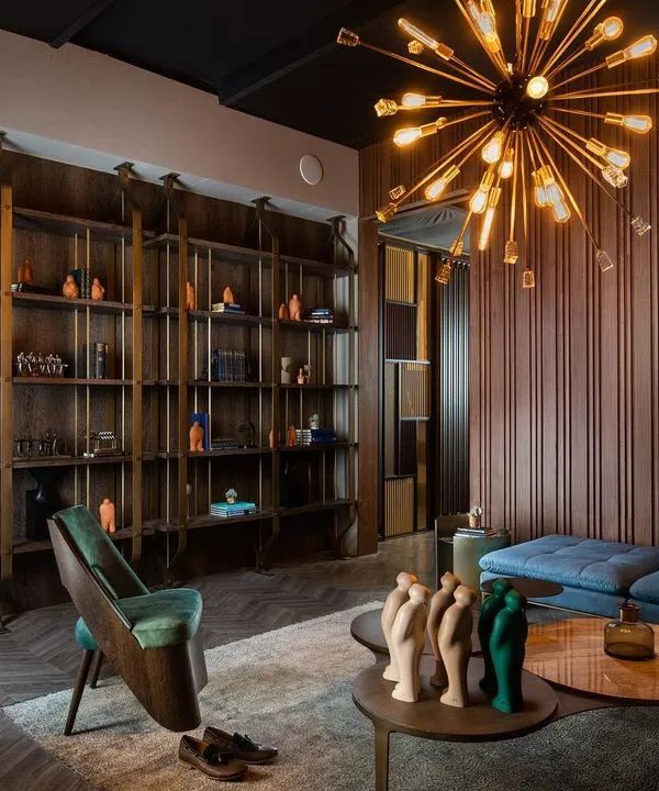 In this living area, the rich wood panelling is complemented by a custom library unit fabricated in a combination of metal and veneer. The panelling serves as a sophisticated foundation for the entire room's design.