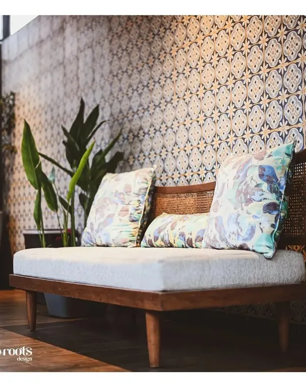 We created this cozy seating nook against a backdrop of beautiful Moroccan-style patterned tiles. The wooden bench with cane detailing and floral cushions adds a touch of bohemian charm, perfect for a quiet corner of a patio or balcony.