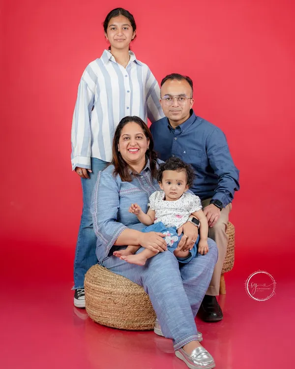 A classic family portrait against a vibrant red backdrop. I work to make everyone feel relaxed, resulting in genuine smiles and a beautiful photo that captures this moment in your family's life.