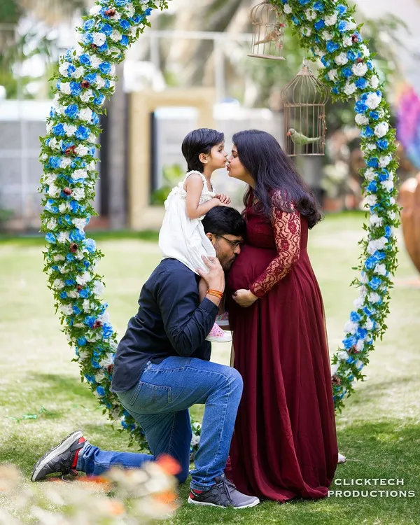 A perfect family portrait full of love and anticipation. This pose, with the daughter on her father's shoulders kissing her mom, is a beautiful way to include siblings in the maternity journey.