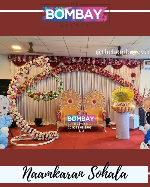 A grand stage setup for a Naamkaran Sohala. This features throne-like chairs for the parents, a floral arch, and our popular shell prop for the name reveal.