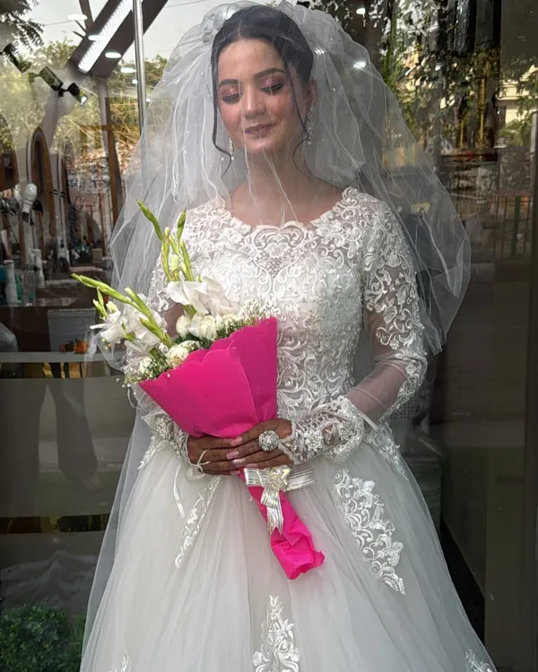 A beautiful bride in our classic long-sleeved Christian wedding gown. The intricate lace detailing on the sleeves and bodice, paired with a simple veil, creates a look of timeless elegance.