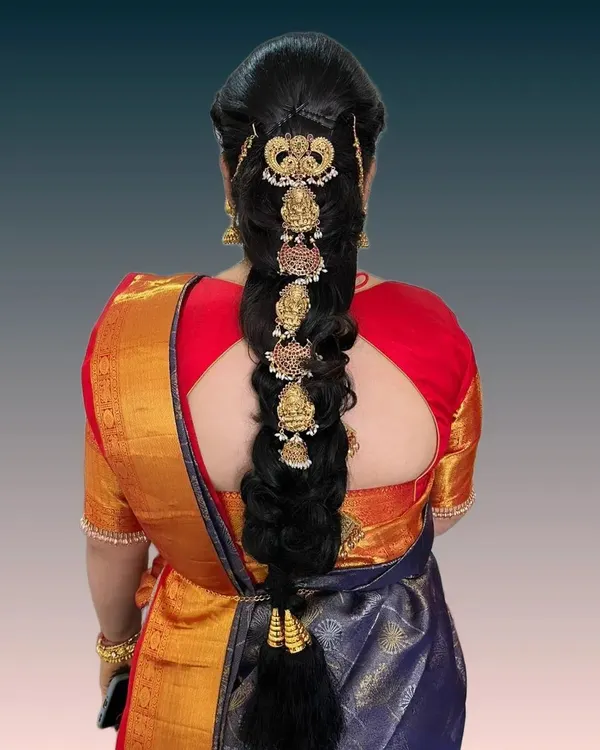 An intricate bridal braid featuring traditional temple jewelry pieces set along its length. This hairstyle is a statement of heritage and is designed to be the crowning glory of a South Indian bridal ensemble.