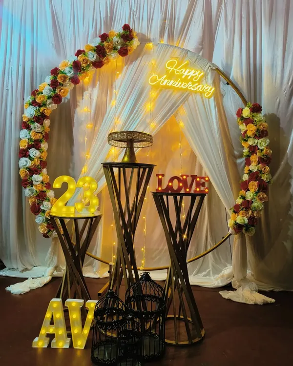 This setup showcases multiple light-up elements working together. It features the number '24' for the anniversary year and the couple's initials 'AV' in marquee letters, complemented by a 'Happy Anniversary' neon sign.