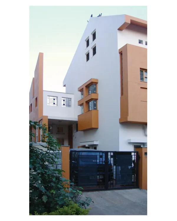 The facade of 'Nachiar Illam', a split-level residence in Bangalore. This project demonstrates our expertise in designing for corner plots with steep slopes, creating a unique modular exterior and allowing for practical entry and parking on two different levels.