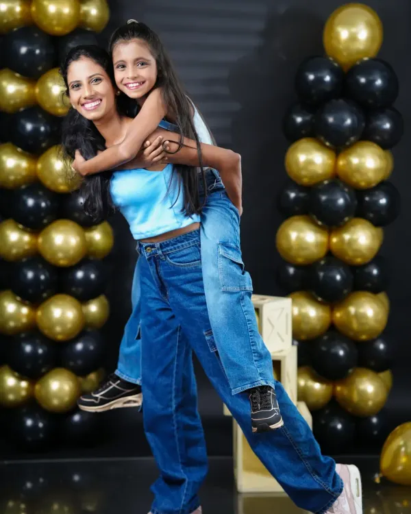 A fun piggyback ride between sisters during a birthday photoshoot. Our studio with black and gold balloon pillars provides a chic and celebratory setting.