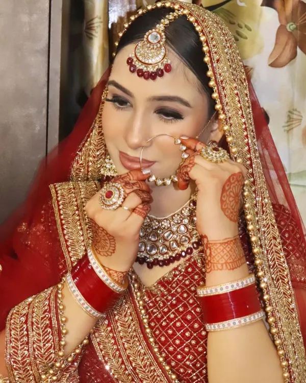 A classic bridal pose, adjusting the nose ring. This look features a sharp cut-crease eye makeup style and a matte red lip, techniques we practice extensively in my professional makeup course.