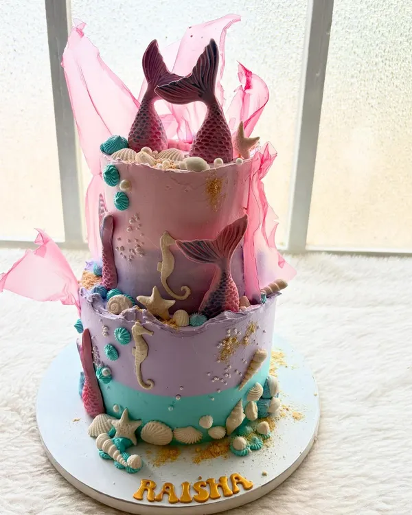 An enchanting two-tier mermaid cake. I used shades of pastel purple, pink, and teal, and decorated it with handcrafted mermaid tails, seahorses, and seashells.