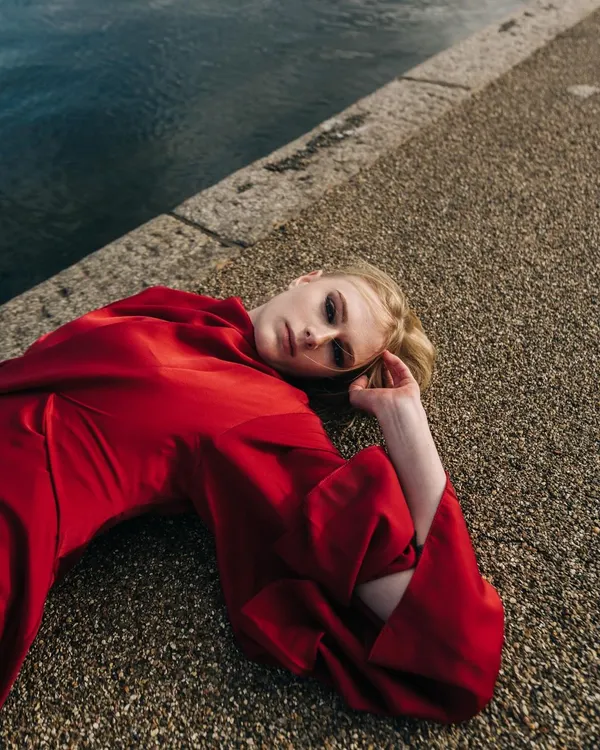 An overhead shot from my first editorial in London. The model lies on the concrete embankment, with the rich red dress creating a striking contrast against the cool tones of the water and stone.