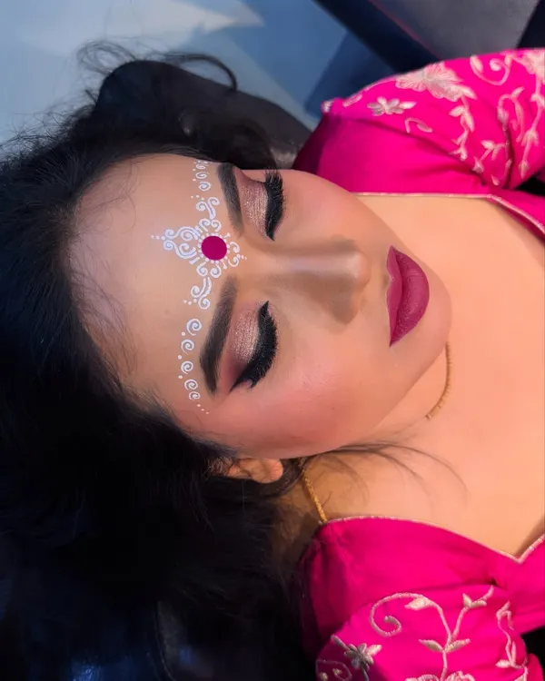 A close up of the traditional Bengali bridal eye makeup and chandan art. The white and red design on the forehead is a beautiful cultural element.